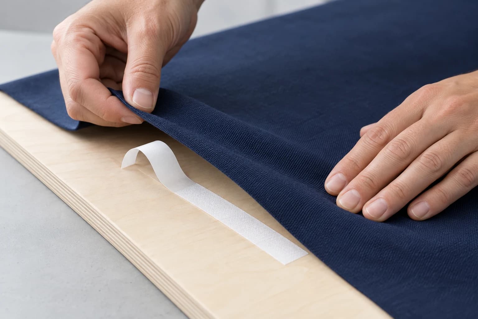 Illustrative navy fabric mounting onto a smooth plywood display panel using a narrow strip of cloth tape